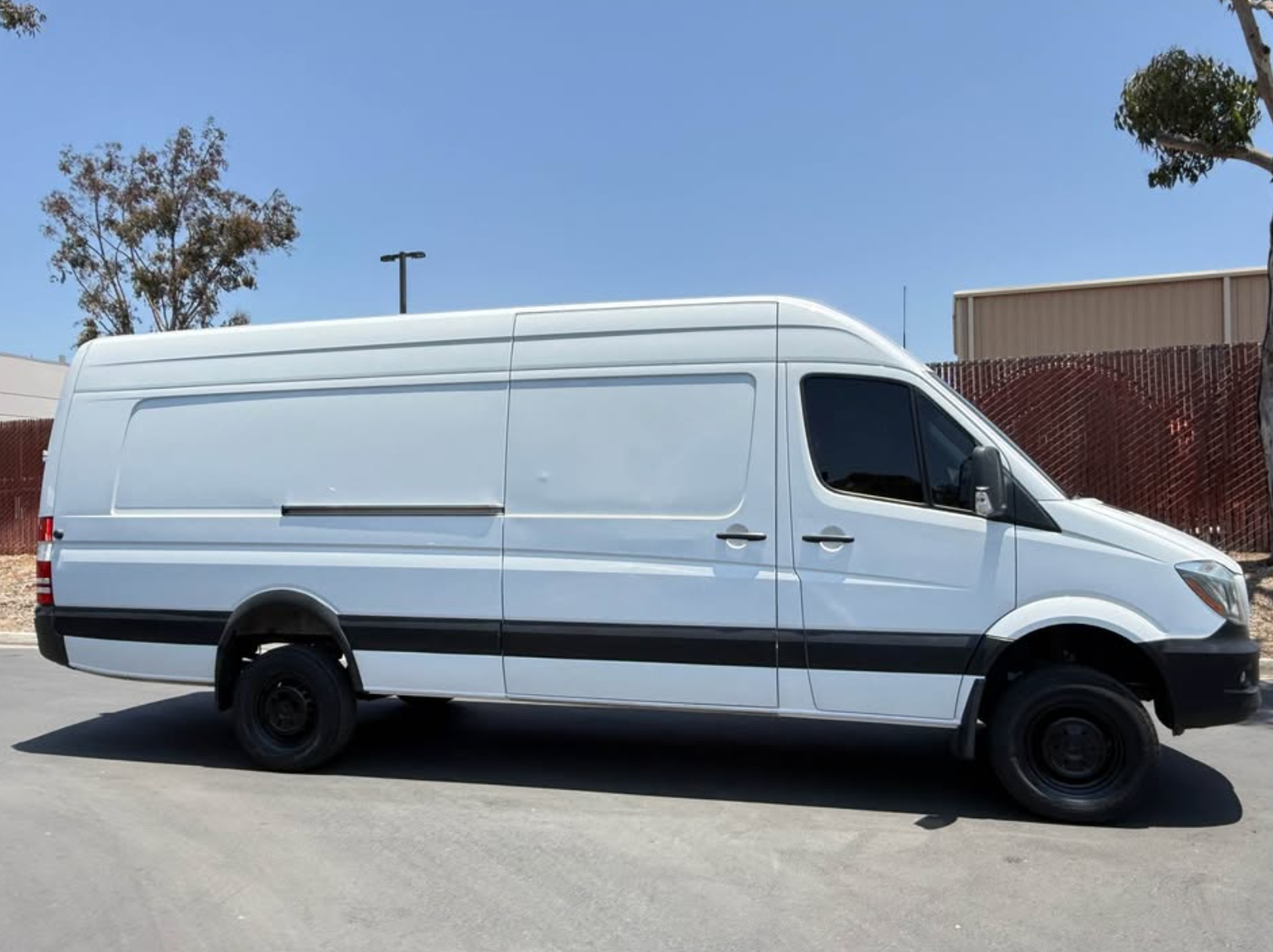 White van parked on a paved surface with a clear blue sky in the background