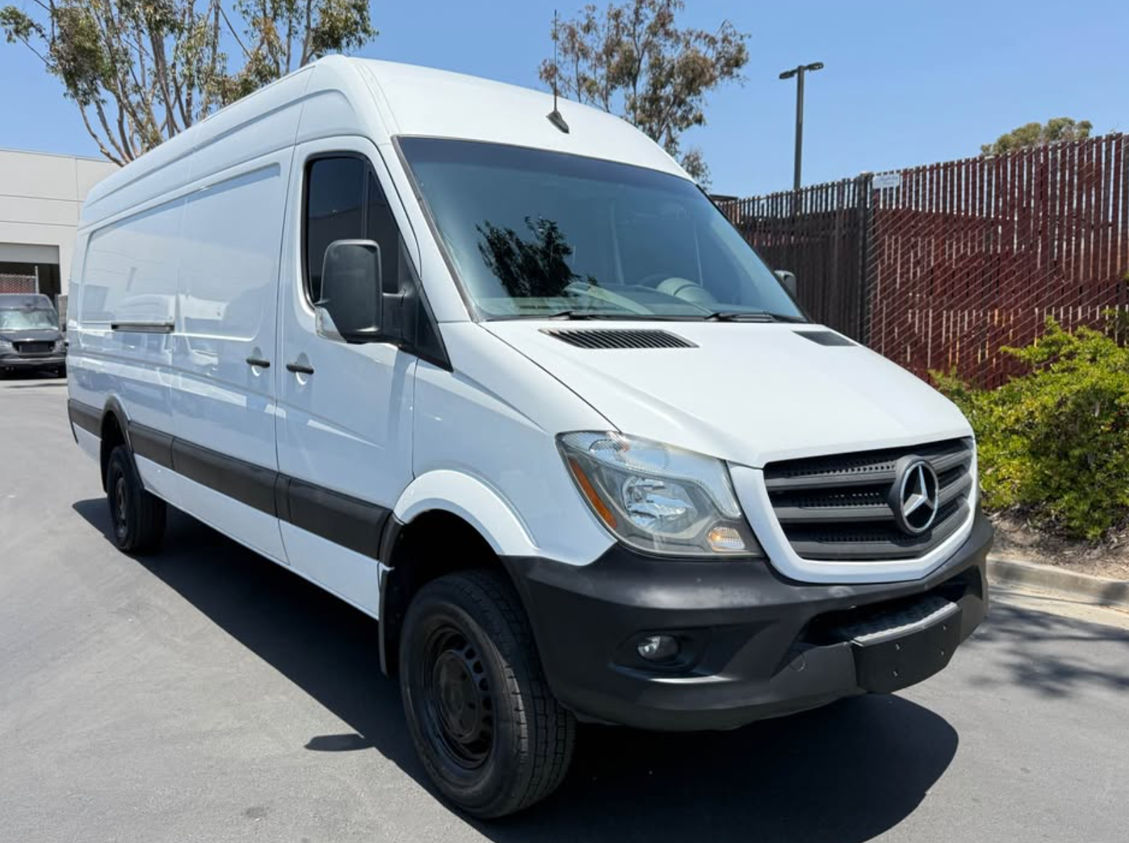White Mercedes-Benz van parked on a street with a clear sky background
