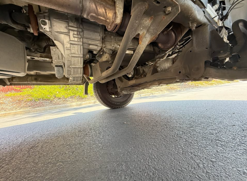 Close-up view of a vehicle's undercarriage on a road.