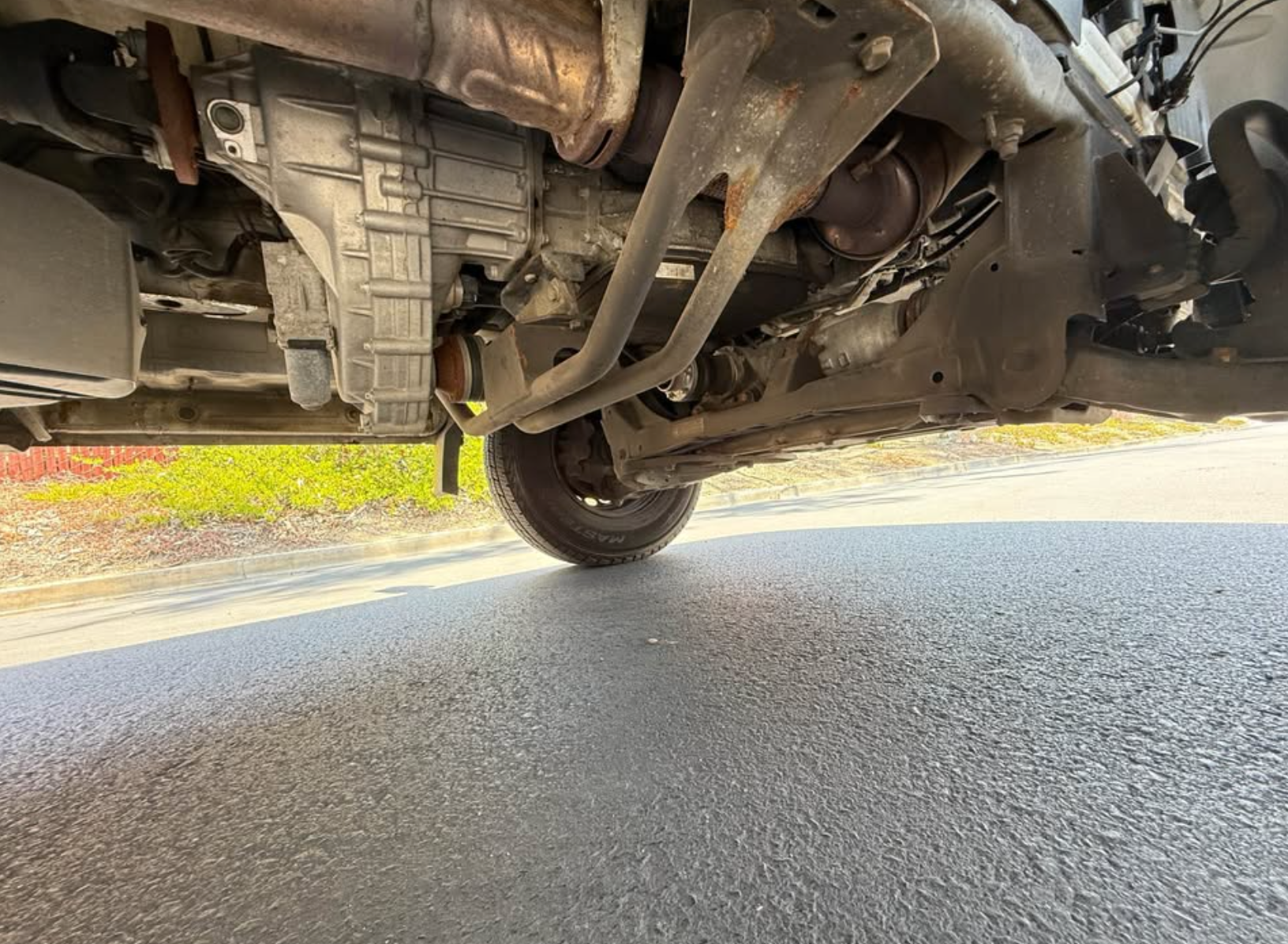 Close-up view of a vehicle's undercarriage on a road.
