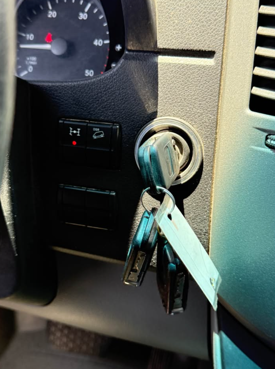 Car keys inserted into a ignition lock on a car dashboard.